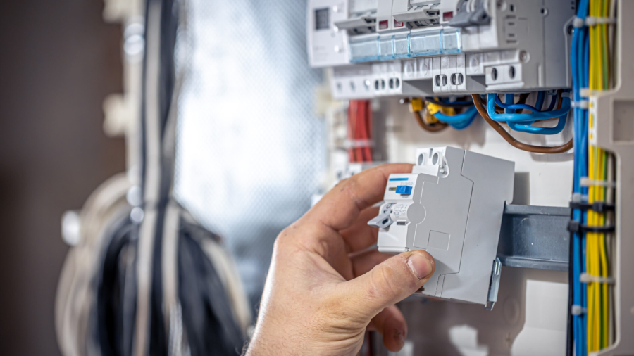 Male electrician at the checkout counter on a blurred background of a switchboard.