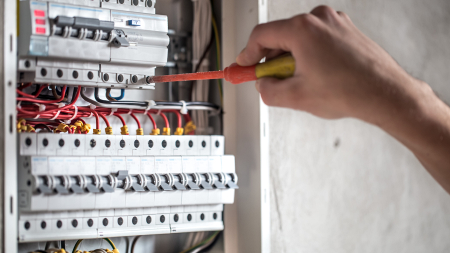Man, an electrical technician working in a switchboard with fuses. Installation and connection of electrical equipment. Professional with tools in hand. concept of complex work, space for text. SSUCv3H4sIAAAAAAAEAI1Ry27DIBC8V+o/WJxjyS44dfoHPVTqPephgW2MQiDi0SqK8u8FEypOVW/szDK7s3N9fOg6wsErQV66a65SrbSOPjgIypoED5s77tBIdC2CUgXrFOgW5BDEYuCECTRR6wzfVpL4ACF69HnYHRIQ8JA0CvgrUTbal7qrxEqmH4ki72jPGsmmYXzkmXlTXqDWYNBGTyp/2/wh9mpktpyd/F+wPD6qbzigEZfVWmPZoUYolvellRy/A7pTewSIUtnG/5cVoHMDbZTOTgllDs03G5Y1j/pN2GiCyyuQaoNoa8/AdQ7jM2lixRfwPrXLijeDRDqFPTVzjA2rgbsqkSmzXI70aZwZm9g4Pm/pPLCB1JytOCrZWizRLypR7tLgKm9AKBspbjnrd9M09IzKqd9tJeufZ05nKjgIBunwtx9tVYW8sQIAAA==